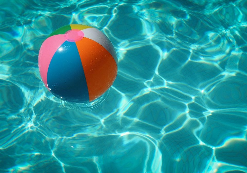 colourful beach ball floating in swimming pool how to save money during summer ukds money tips blog