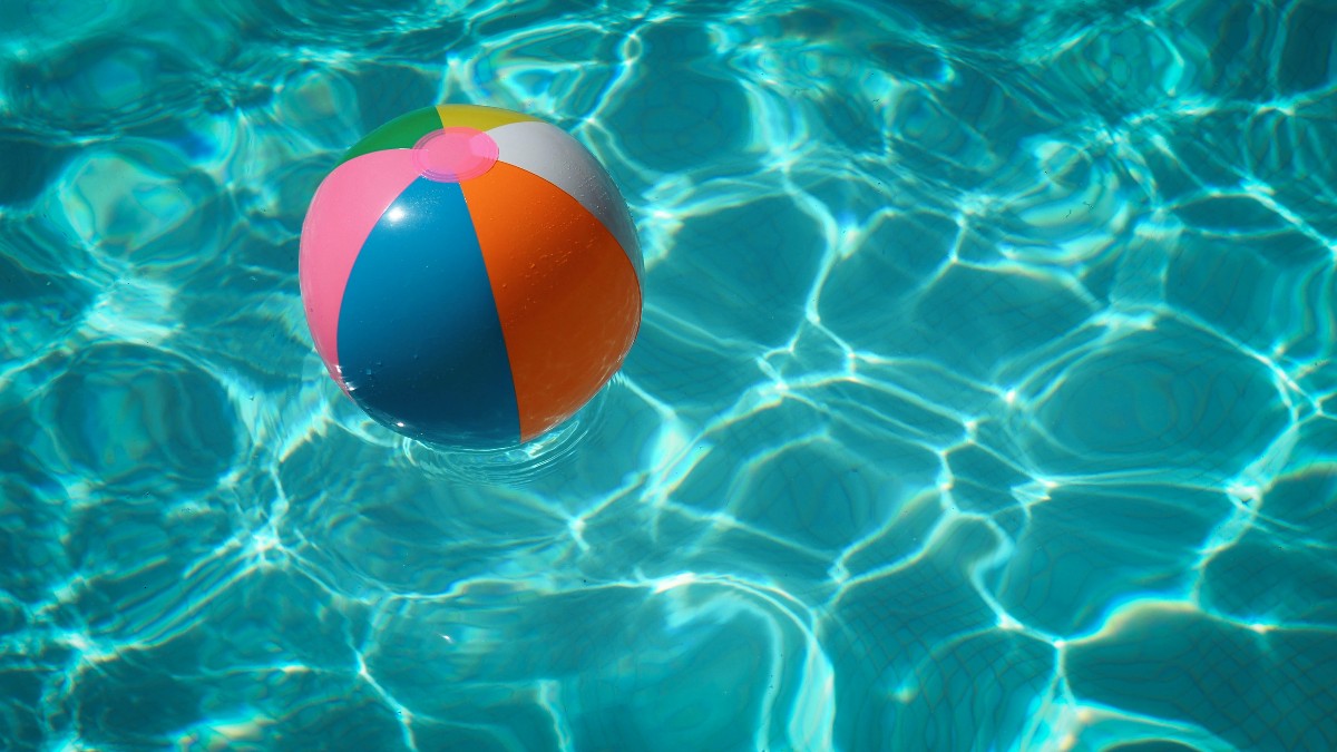 colourful beach ball floating in swimming pool how to save money during summer ukds money tips blog