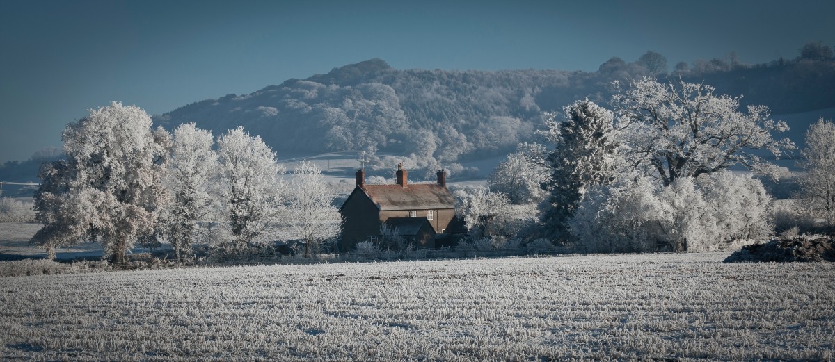 winter-proof your home ukds blog snow speckled house in a field surrounded by trees